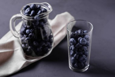 Koyu beton arka planda bir sürahi ve cam yaban mersini. Detoks, smoothie yapımı, böğürtlen hakları konsepti.