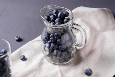 Gri beton arka planda cam sürahide yabanmersini. Meyvelerin faydaları, vejetaryenlik kavramı.