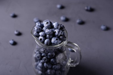 Gri beton arka planda cam sürahide yabanmersini. Meyvelerin faydaları, vejetaryenlik kavramı.