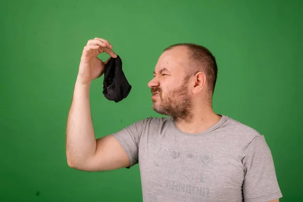 Mann Mittleren Alters Schnüffelt Stinkenden Socken Auf Grünem Hintergrund Wäsche — Stockfoto