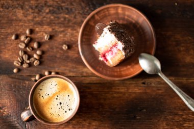 Bir fincan kahve ve koyu ahşap arka planda bir parça kek..