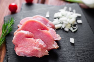 Dilimlenmiş çiğ hindi eti, doğranmış soğan, siyah bir arkaplanda..