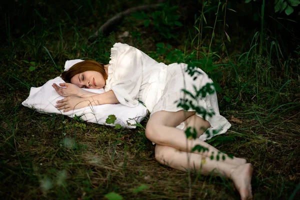 Healthy sound sleep. Rest, relaxation in the forest. Woman sleeps on a pillow on a green glade in the forest.