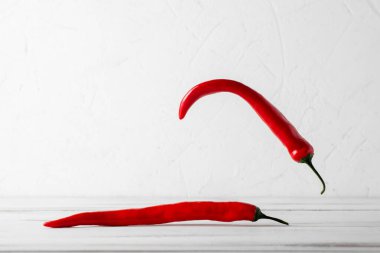 Beyaz ahşap arka planda kırmızı kırmızı kırmızı biber kokusu var. Yiyecek havalanması.