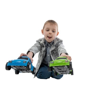 Genç çocuk beyaz arka planda izole edilmiş çok renkli oyuncak arabalarla oynuyor. Çocuk eğlencesi, eğlence..