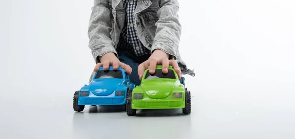 Een Jonge Jongen Speelt Met Veelkleurige Speelgoedauto Een Witte Achtergrond — Stockfoto