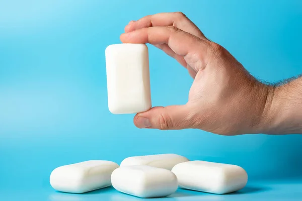 stock image Global Handwashing Day. A bar of soap in a man's hand on a blue background. Personal hygiene concept, hand washing.