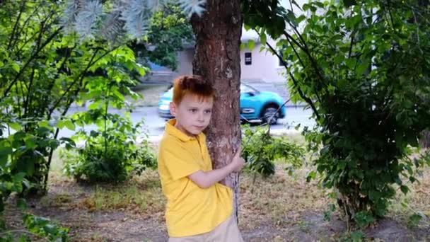 Rudovlasý Chlapec Žlutém Tričku Stromu Městě Kolem Projíždějí Auta — Stock video