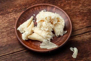 Ahşap bir zeminde, kil tabakta dilimlenmiş sert peynir cipsi..