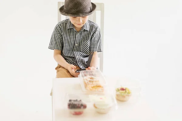 Ragazzo Con Camicia Cappello Siede Davanti Delle Torte Con Telefono — Foto Stock