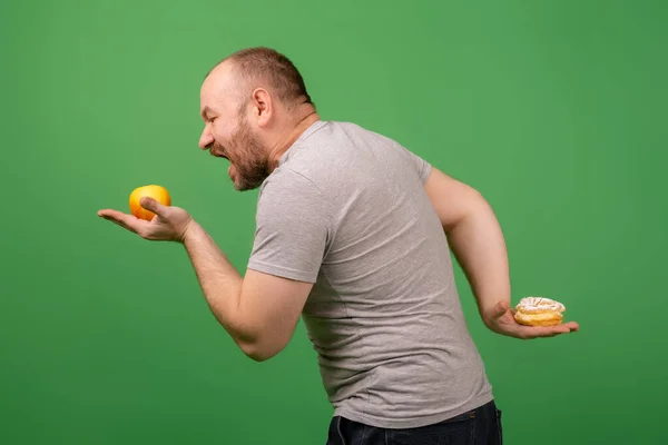 Ein Mann Mittleren Alters Wählt Apfel Gegen Brownie Auf Grünem — Stockfoto