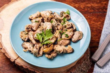 Koyu ahşap arka planda soyulmuş soslu midyeler..