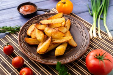 Masadaki tabakta farklı sebzelerle birlikte büyük parçalar halinde kızarmış patates..