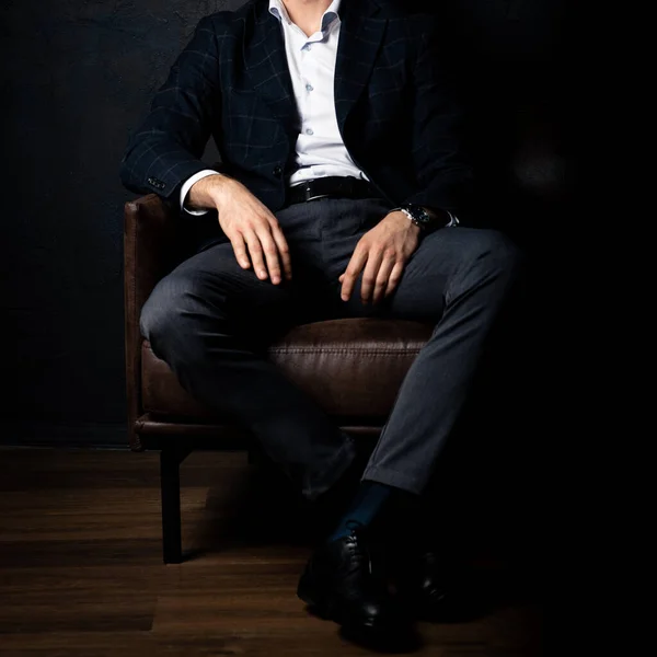 Tanınmayan stil sahibi maço adam karanlıkta koltukta rahatça oturuyor..