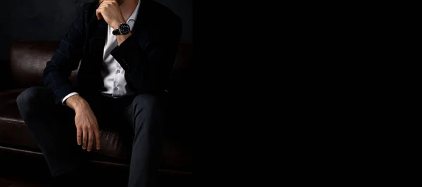 Tanınmayan stil sahibi maço adam karanlıkta koltukta rahatça oturur. Pankart, metin için yer.