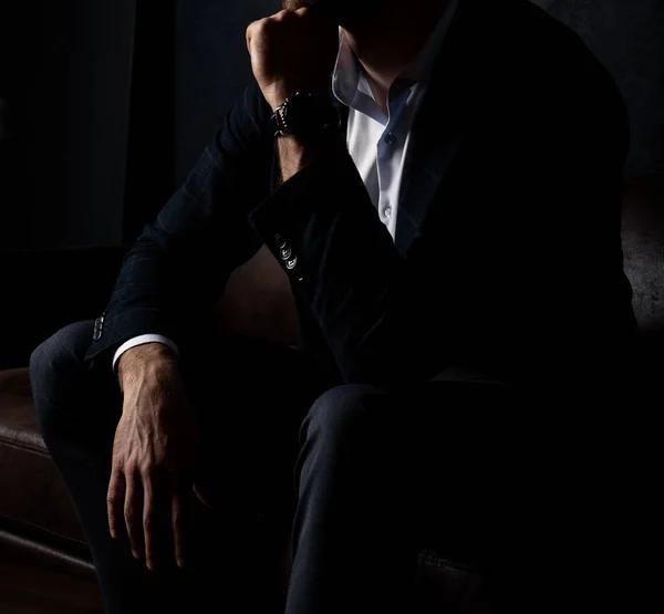 Tarz sahibi kıyafetleri içinde tanınmayan bir adam karanlıkta kanepede rahatça oturur..