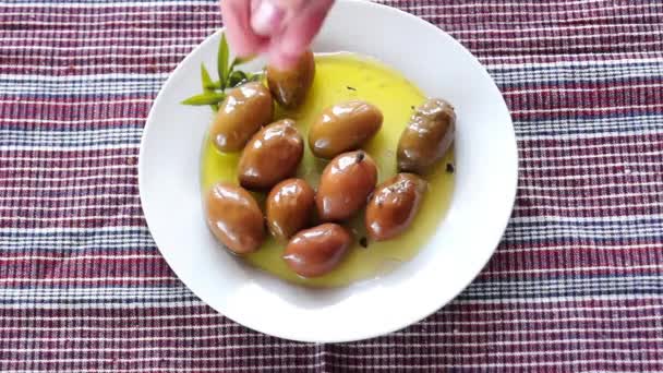 Zugabe von rotem und schwarzem Pfeffer zu grünen Oliven — Stockvideo