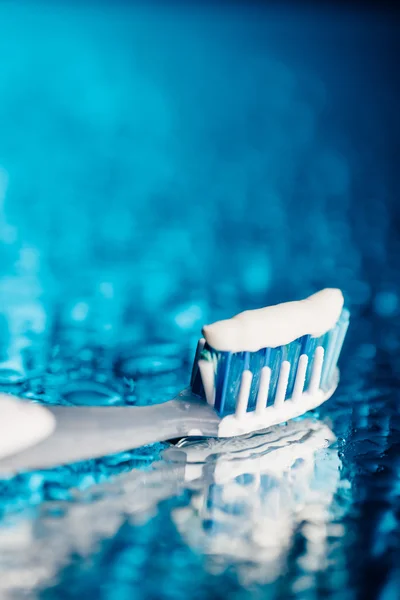 Toothbrush on blue background with water drops — Stock Photo, Image