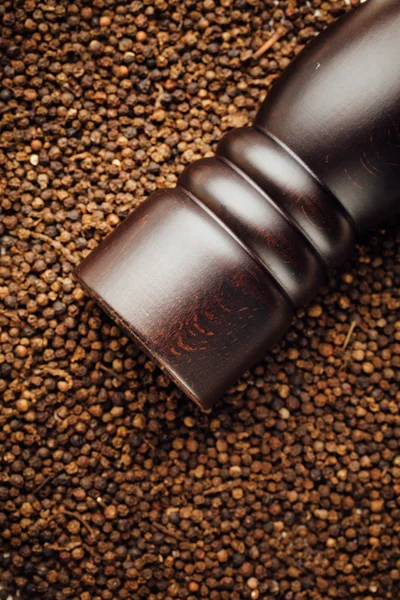 Pepper mill on peppercorns background — Stock Photo, Image
