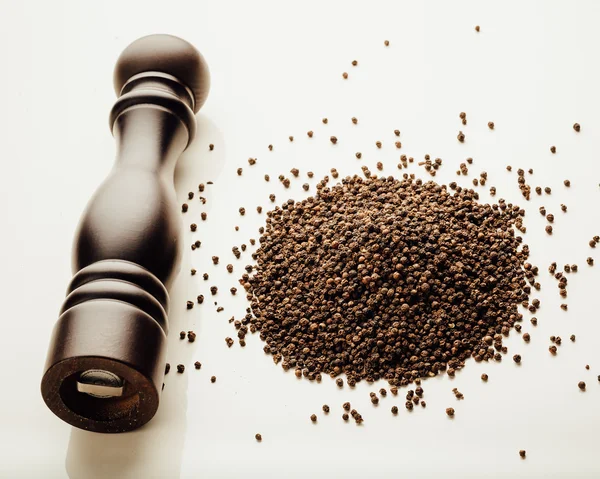 Pepper mill and peppercorns heap, white background — Stock Photo, Image