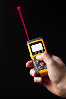 lazer mesafe ölçer elinde, siyah arka plan