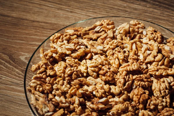 Nueces sin cáscara en un plato, fondo de madera — Foto de Stock