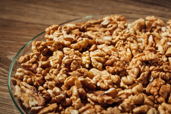 Nueces sin cáscara en un plato, fondo de madera — Foto de Stock