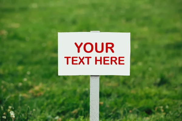 Your text here sign against green grass background — Stock Photo, Image