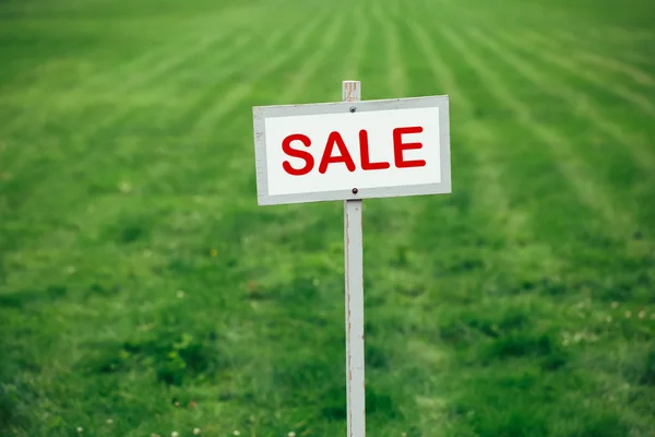 sale sign against trimmed lawn background