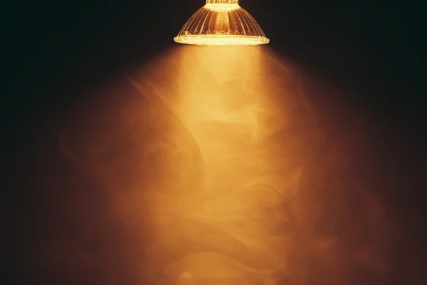 Halogen lamp with reflector, warm light in fog — Stock Photo, Image