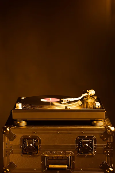 Professional dj turntable on flight case, dark background, golden tone — Stock Photo, Image