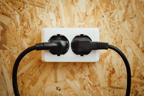 Enchufe y enchufe de corriente alterna, fondo de pared osb de madera —  Fotos de Stock