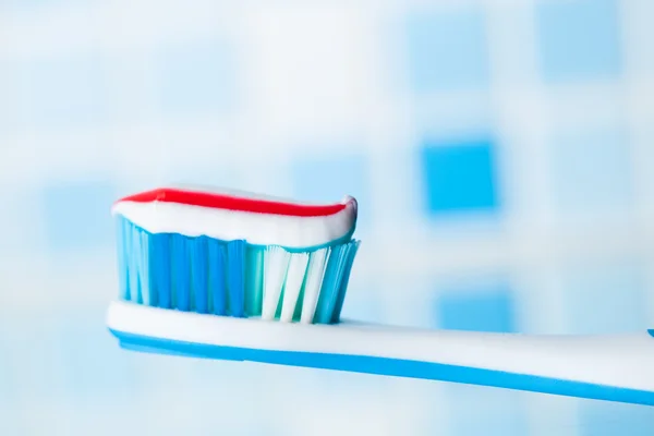 Kırmızı çizgili diş macunu ile mavi diş fırçası — Stok fotoğraf