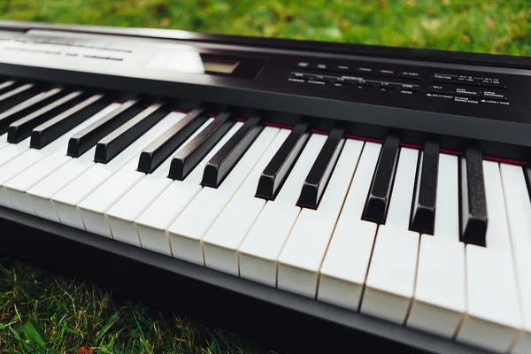 Elektrikli piyano klavye, yeşil çim arka planın parçası — Stok fotoğraf