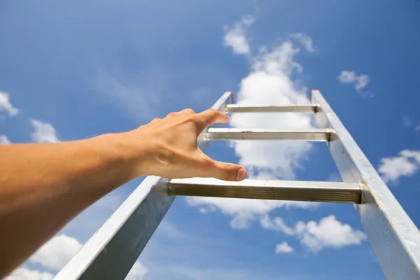 Mão mexendo uma escada, fundo céu azul — Fotografia de Stock