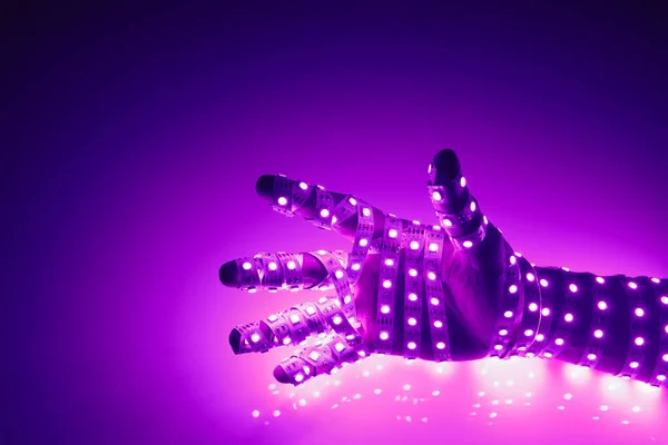 human hand covered with purple led lights, illuminated background