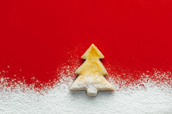 クリスマスツリークッキーと華やかな雪 赤い紙の背景 — ストック写真