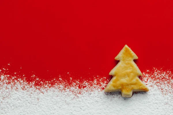 クリスマスツリークッキーと華やかな雪 赤い紙の背景 — ストック写真
