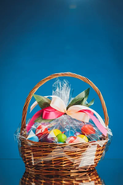 Easter gift basket with multicolor eggs, blue background