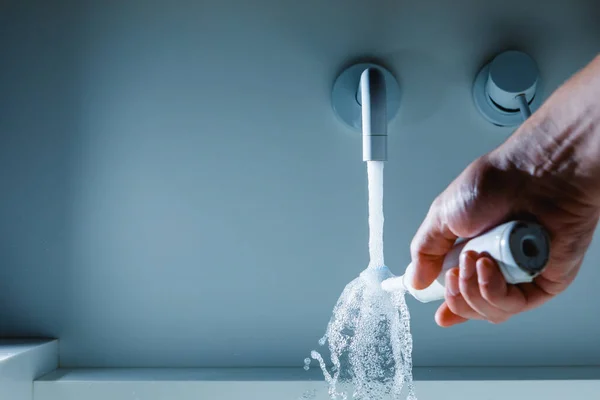 Mano Sosteniendo Cepillo Dientes Bajo Agua Que Fluye Del Grifo —  Fotos de Stock