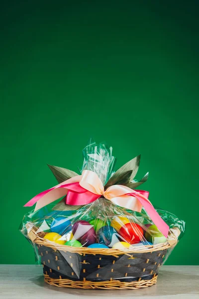 Easter gift basket with multicolor eggs, green background