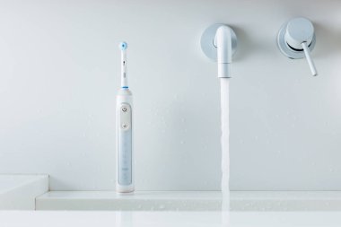 elektrikli diş fırçası bir çamaşır kabında, musluktan akan su