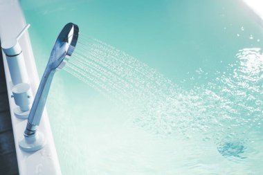 Küveti suyla dolduran bir duş.