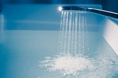 Küveti suyla dolduran bir duş.