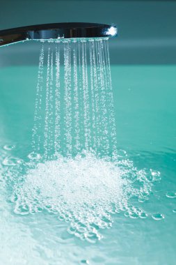 Küveti suyla dolduran bir duş.