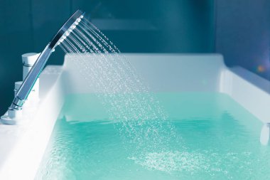 Küveti suyla dolduran bir duş.