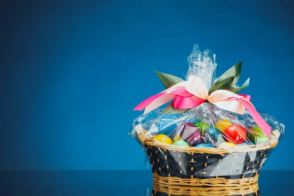 Easter gift basket with multicolor eggs, blue background