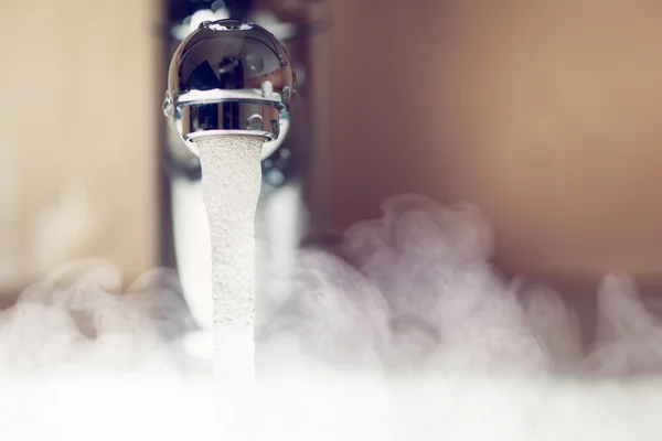 Wasserhahn mit heißem Wasserdampf Stockbild