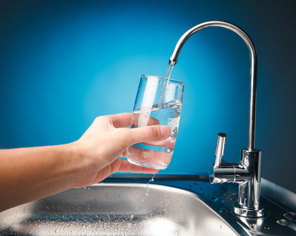 hand pouring a glass of water from filter tap