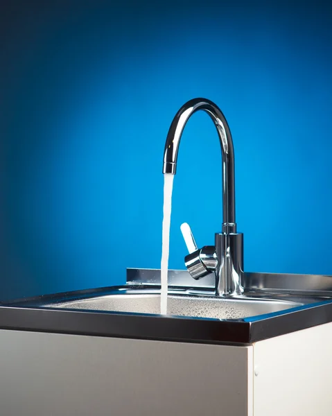 Miscelatore rubinetto con acqua corrente, fondo blu — Foto Stock